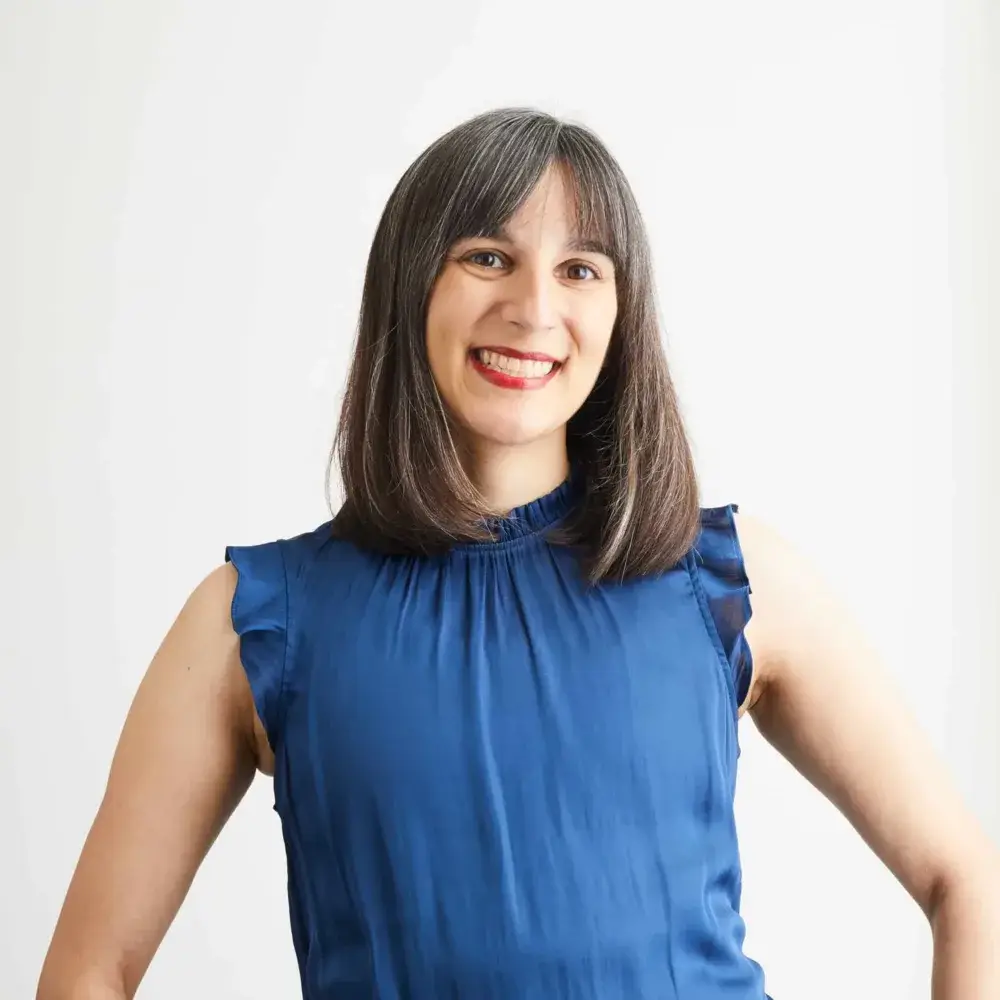Woman smiling in blue blouse with white background.