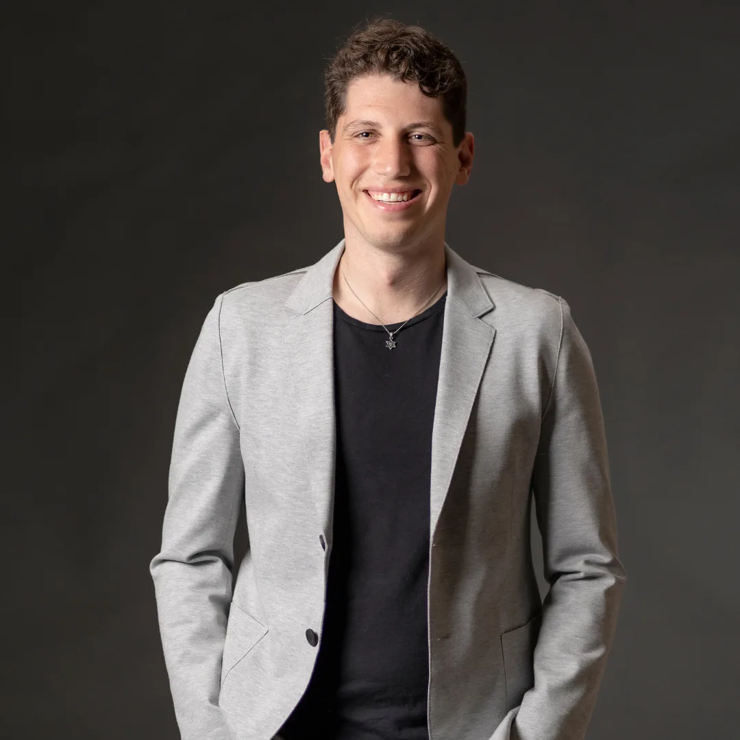 Smiling person in gray blazer and black shirt.
