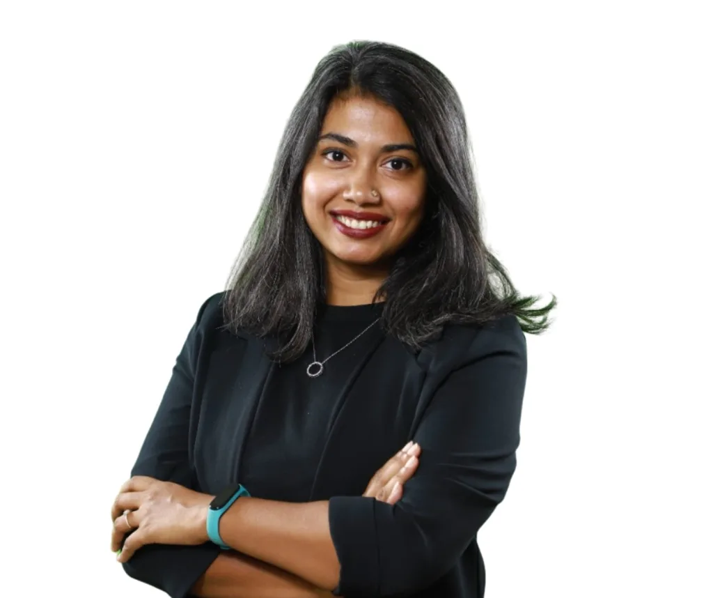 Smiling person with folded arms in black outfit.