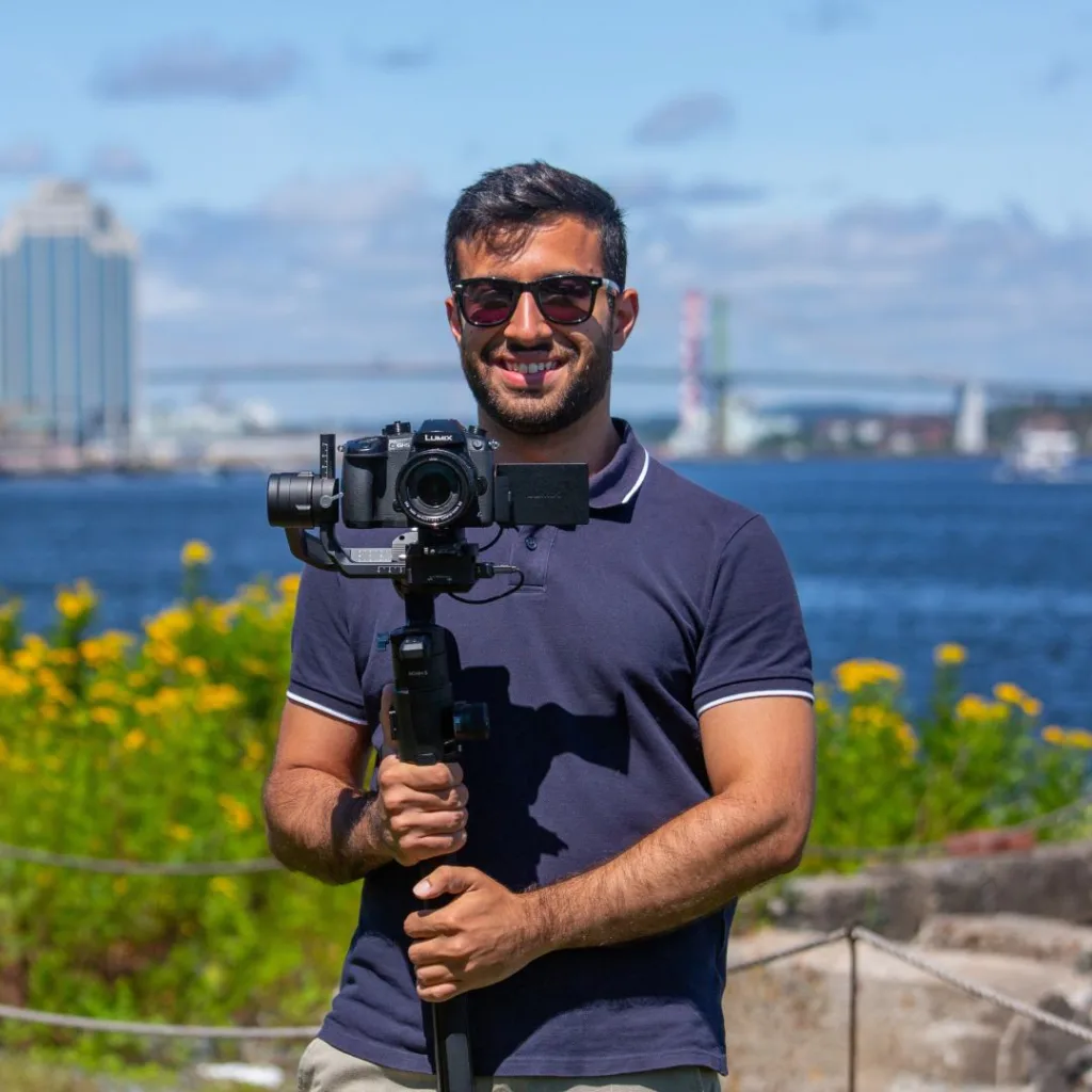 Man filming by waterfront with camera stabilizer.