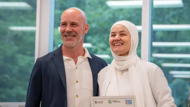 Smiling people holding award certificate indoors.
