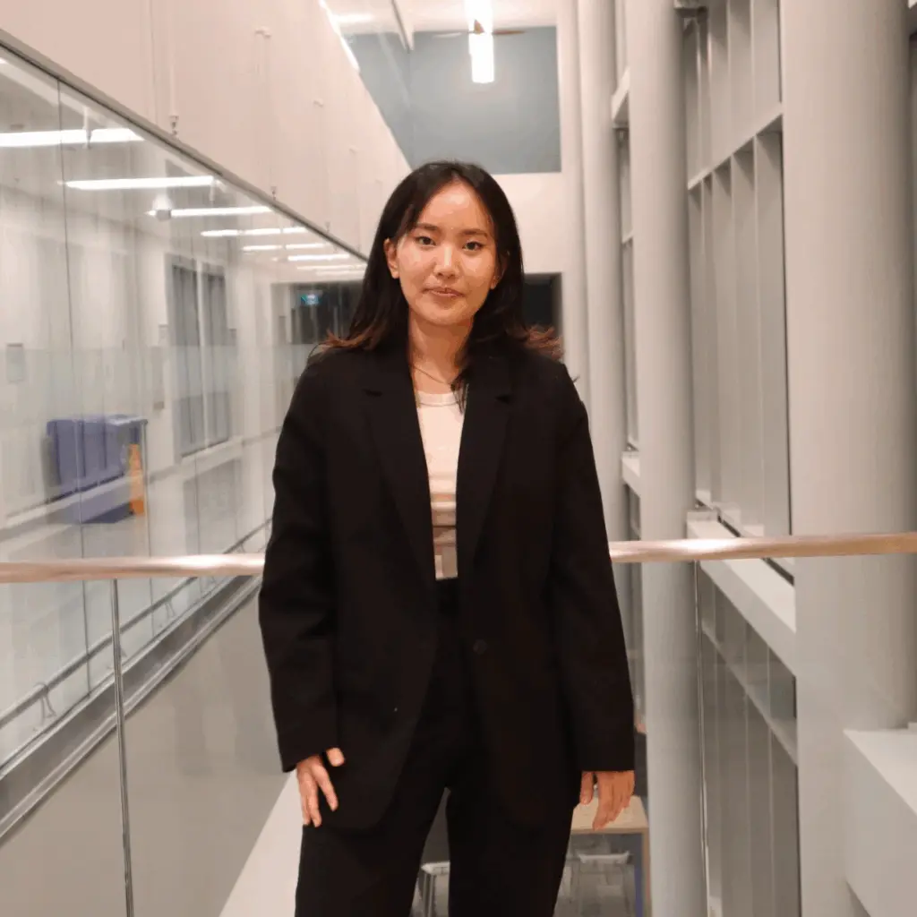 Person in office hallway wearing a black blazer.