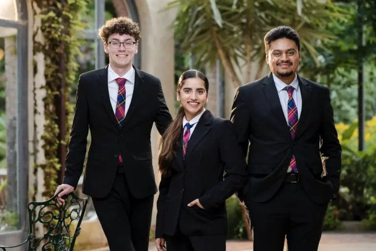 Three people in suits smiling outdoors
