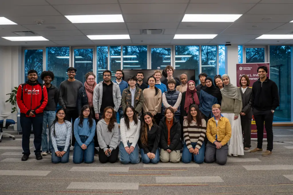 Diverse group of students gathered indoors smiling.