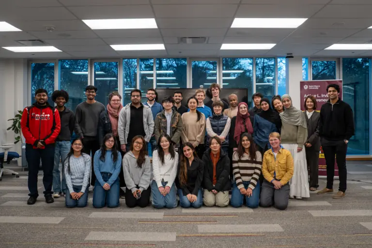 Diverse group of students gathered indoors smiling.