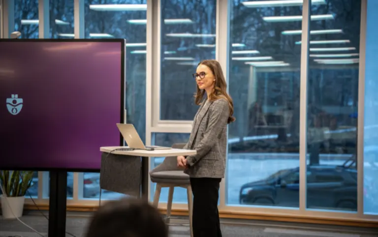 Woman presenting in front of screen and laptop.