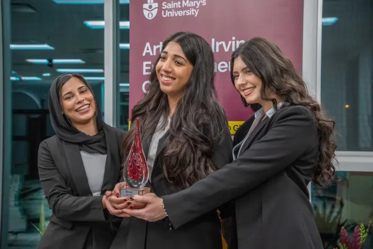 Three women holding a business award trophy.
