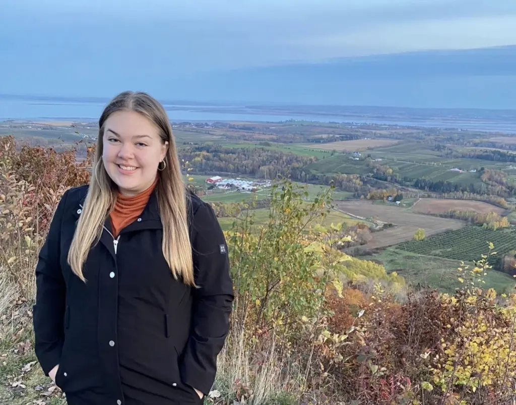 Smiling person standing on scenic hilltop in autumn.