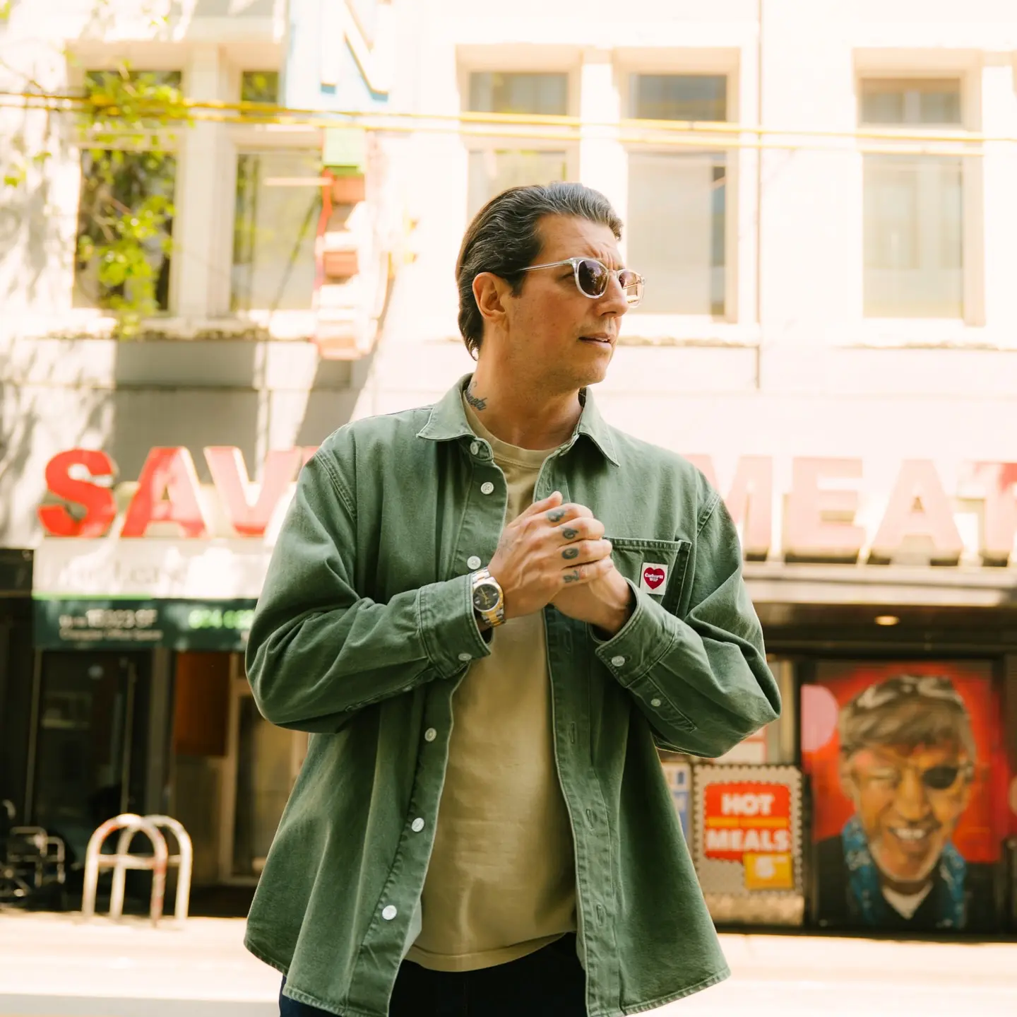 Man in denim shirt standing outside.