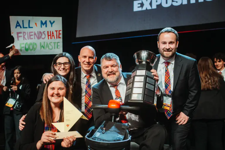 Group celebrating with trophy and sign