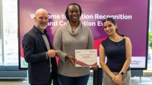 Three people holding certificate at recognition event