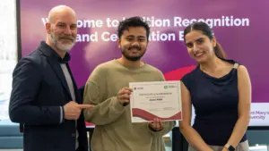 Student holding certificate with presenters at recognition event