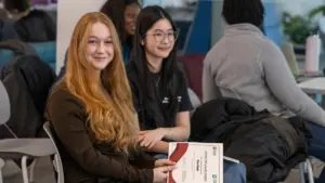 Two students holding certificate in classroom setting