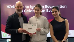 Student holding certificate with presenters at recognition event