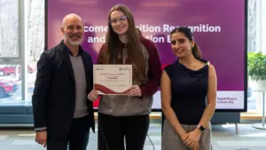 Student holding certificate with presenters at recognition event
