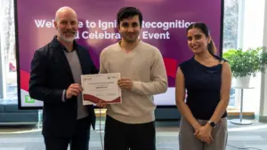 Three people holding certificate at recognition event