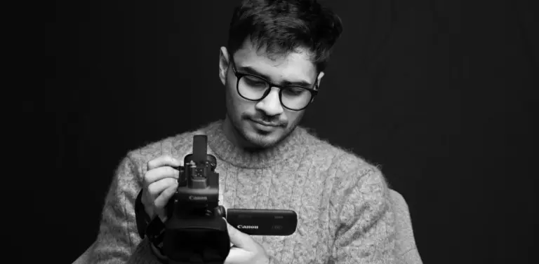 Man with glasses adjusting Canon video camera