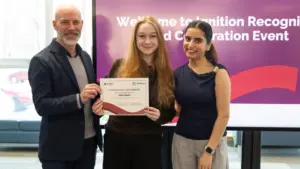 Three people holding certificate at recognition event
