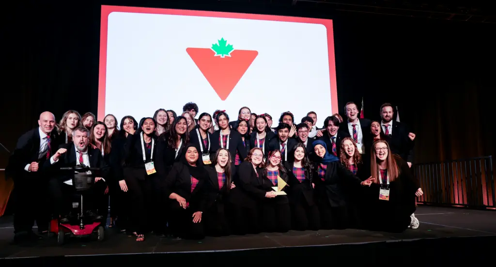 Team celebrating on stage with award and logo backdrop
