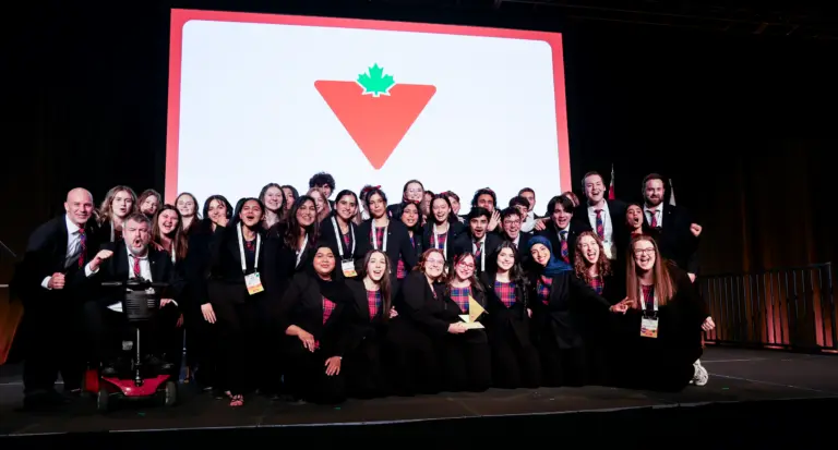 Team celebrating on stage with award and logo backdrop