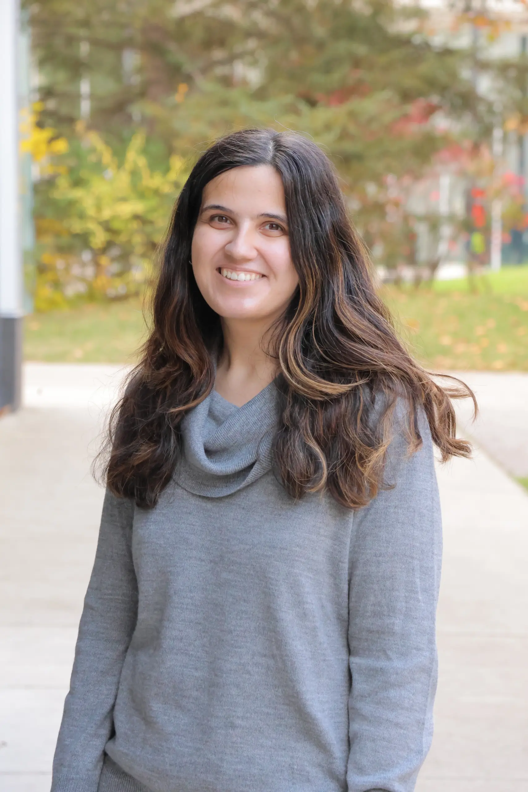 Smiling woman in gray sweater outdoors in autumn