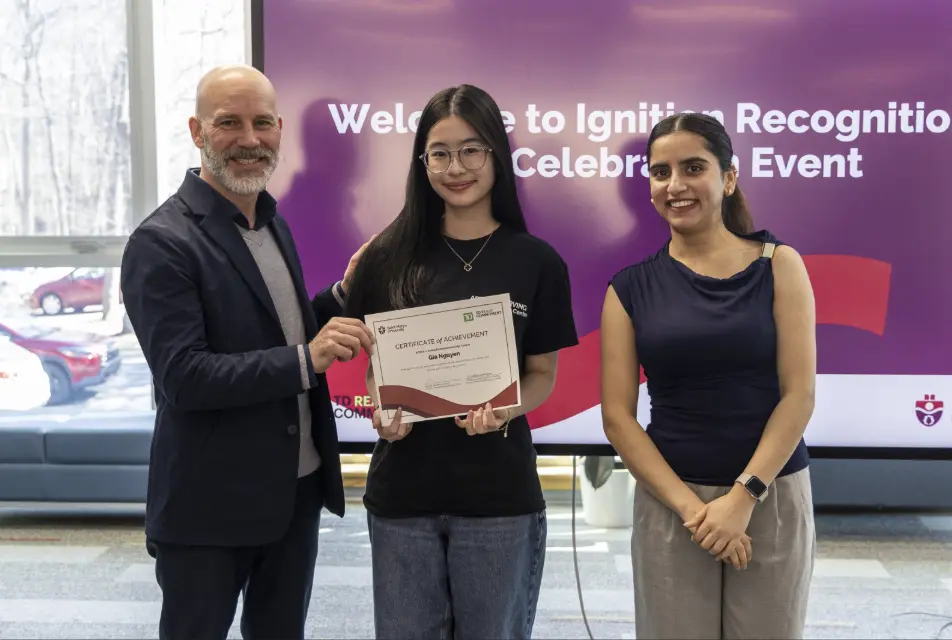 Three people holding certificate at recognition event