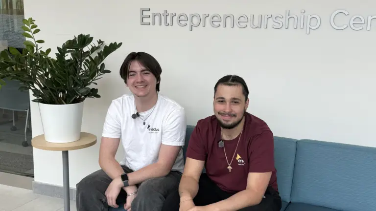 Two students seated at Entrepreneurship Center sign