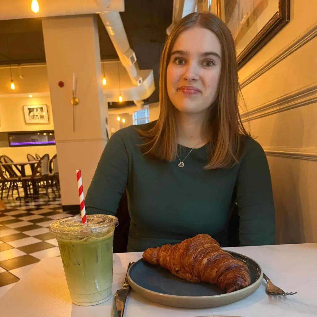 Woman with croissant and matcha latte at cafe