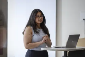 Woman presenting beside laptop at standing desk