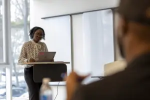 Woman presenting with laptop at podium in classroom