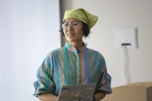 Person in green bandana holding laptop indoors