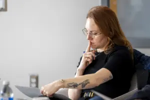 Woman with glasses reviewing document thoughtfully indoors