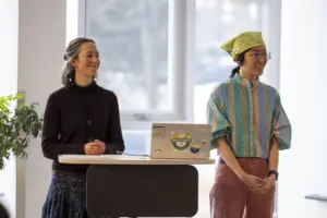 Two women presenting beside laptop at podium indoors