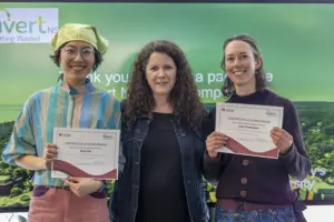 Three women holding certificates at award event