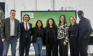 Seven professionals posing before presentation screen