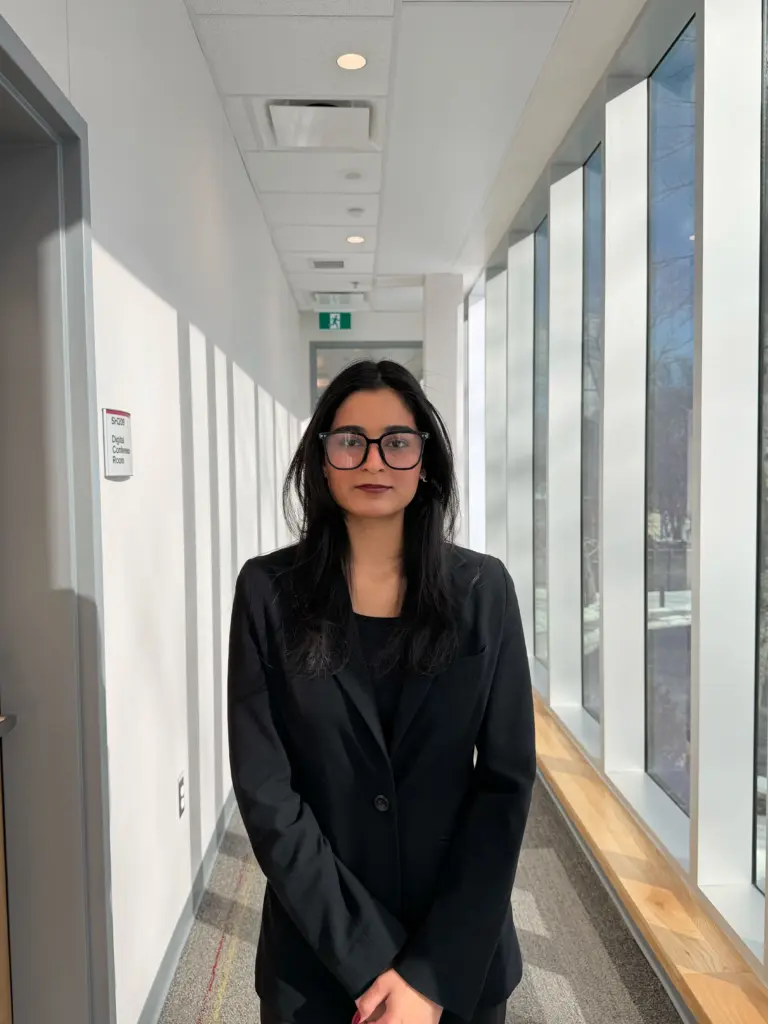 Woman in black blazer standing in office hallway
