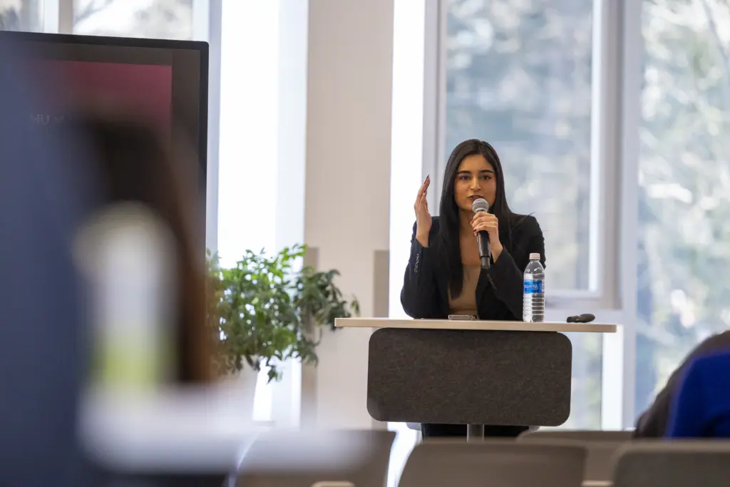 Woman speaking at podium during indoor presentation