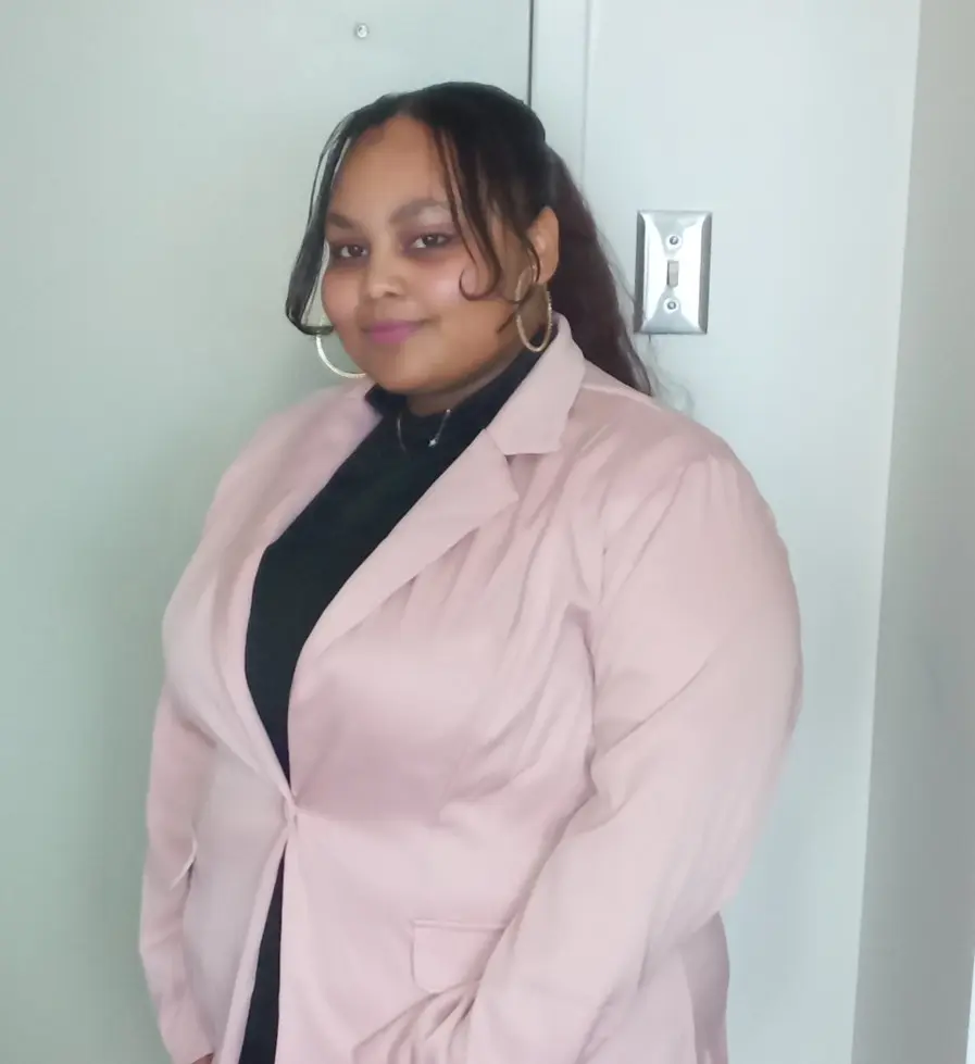 Woman in pink blazer posing indoors
