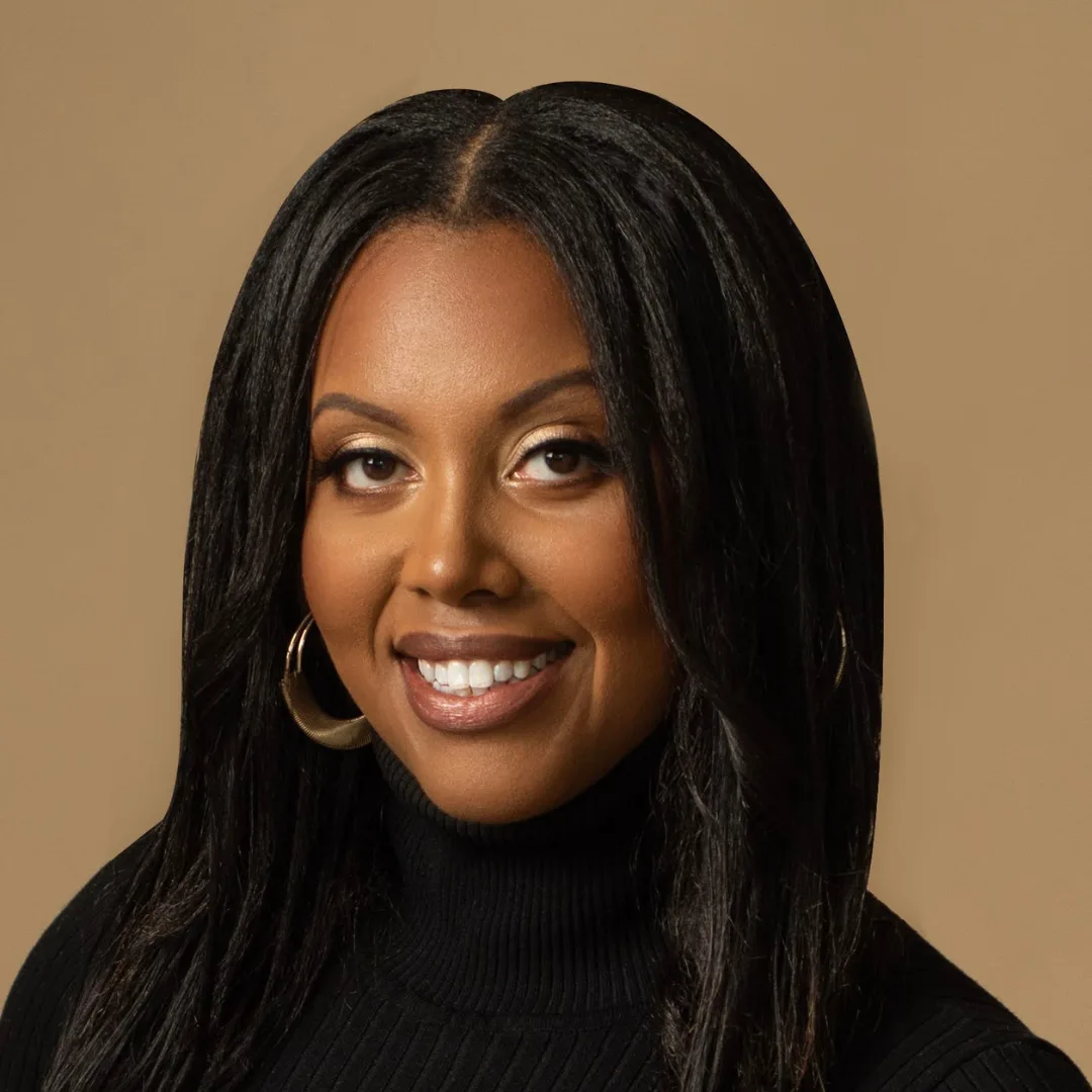 Smiling woman in black turtleneck with gold hoop earrings