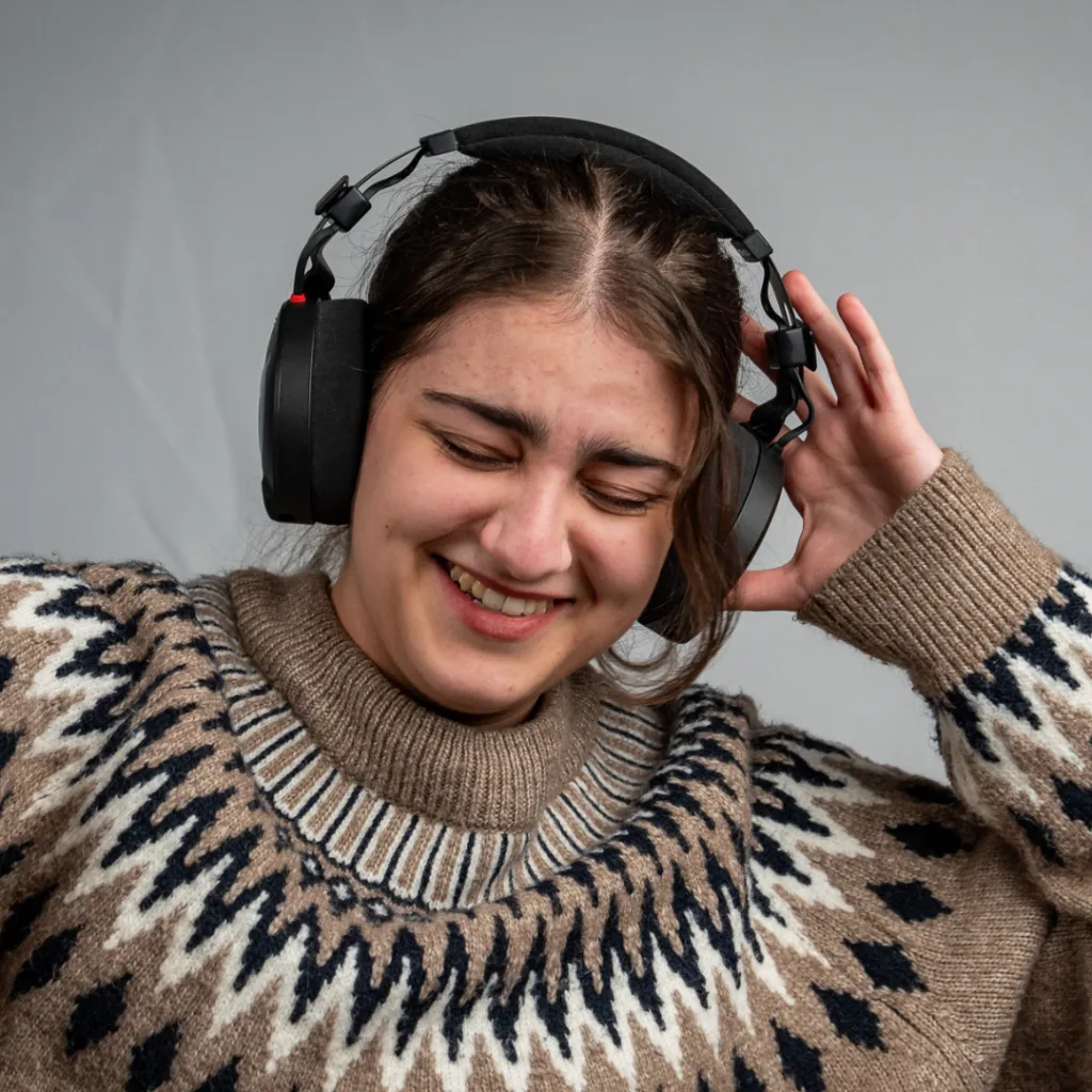 Smiling woman wearing headphones and a patterned sweater
