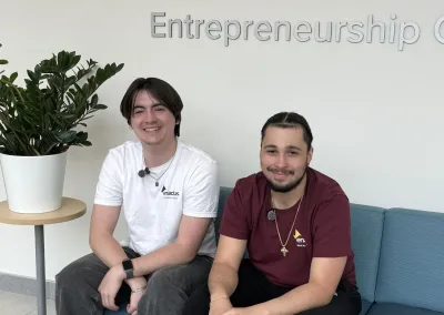 Two students seated at Entrepreneurship Center sign