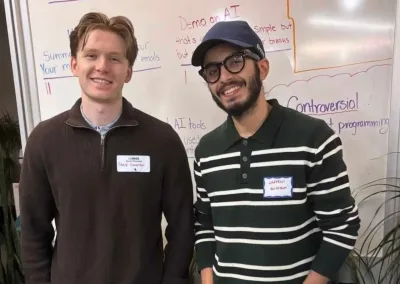 Two men smiling in front of AI whiteboard